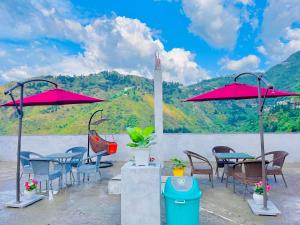 a group of tables and chairs with red umbrellas at River Grand Resort - A Peaceful Stay Kempty Fall Mussoorie in Mussoorie