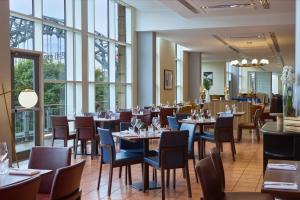 a dining room with tables and chairs and windows at Hilton Newcastle Tyne Bridge in Newcastle upon Tyne