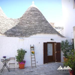 ein weißes Gebäude mit einem steilen Dach und einer Leiter in der Unterkunft Trullo al vicoletto al civico 10, civico 8, civico 7 in Alberobello