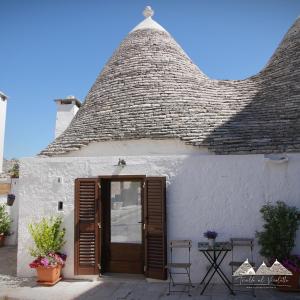 ein weißes Haus mit einem Strohdach und einer Tür in der Unterkunft Trullo al vicoletto al civico 10, civico 8, civico 7 in Alberobello