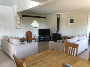 ein Wohnzimmer mit Sofas, einem Tisch und einem TV in der Unterkunft The Stables Kenilworth in Kenilworth