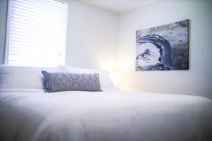 a bedroom with a white bed with a painting on the wall at Sleeps 10! Minutes to Parris Island & Downtown in Beaufort