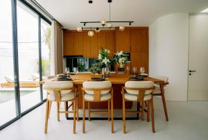 uma sala de jantar com uma mesa de madeira e cadeiras em Garden Villa Pererenan by BREIG em Canggu