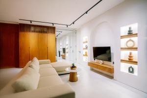 uma sala de estar com um sofá branco e uma televisão em Garden Villa Pererenan by BREIG em Canggu