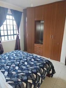 a bedroom with a bed with a blue and white blanket at Ole kerai #101 in Nairobi