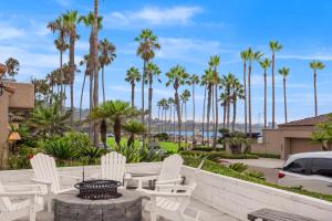 a patio with white chairs and a fire pit with palm trees at By The Sea in San Diego