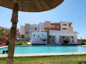 a villa with a swimming pool in front of a house at Tanger plage Al Houara in Tangier