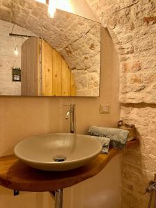 La salle de bains est pourvue d'un lavabo et d'un mur en pierre. dans l'établissement La Casetta, à Alberobello