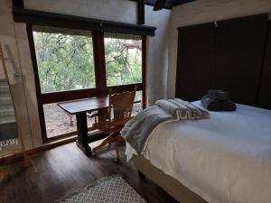 a bedroom with a bed and a desk and a window at Boomhuis, Bela-Bela, Mabalingwe in Bela-Bela