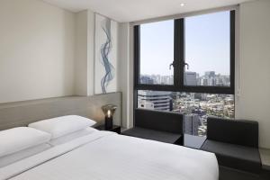 a bedroom with a bed and two chairs and a window at Fairfield by Marriott Seoul in Seoul