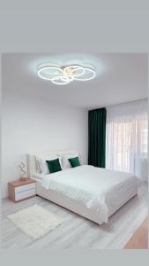 a white bedroom with a large bed and a chandelier at Scandinavia Apartment 1 in Piatra Neamţ
