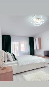 a bedroom with a large white bed with green curtains at Scandinavia Apartment 1 in Piatra Neamţ