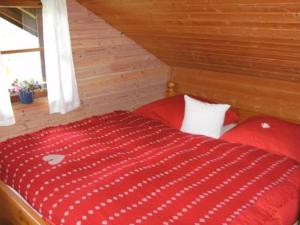 a red bed in a wooden room with a window at Berghütterl - Ferienhaus Ingerlhof in Tegernsee