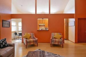 a living room with orange walls and a couch and chairs at Executive Hills in Las Cruces