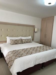 a bedroom with a large bed with a large headboard at Hotel Juan Maria in Tuluá