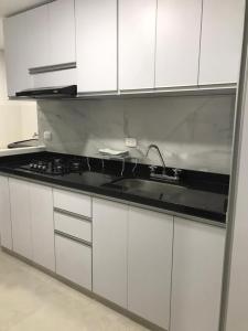 a kitchen with white cabinets and a sink at Apartamento cerca estacion de lagos in Floridablanca