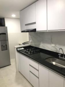 a kitchen with white cabinets and a black counter top at Apartamento cerca estacion de lagos in Floridablanca