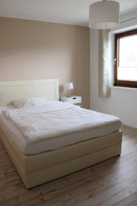 1 cama blanca en un dormitorio con ventana en Ferienwohnung Hans im Glück en Olbernhau