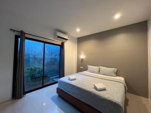 um quarto com uma cama e uma grande janela em Cmon guesthouse em Phetchaburi