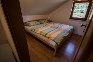 a small bedroom with a bed with a window at Hiša Nataša in Drežnica