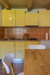 cocina con armarios amarillos, mesa y sillas en Hiša Nataša, en Drežnica