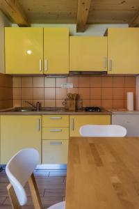a kitchen with yellow cabinets and a table and chairs at Hiša Nataša in Drežnica