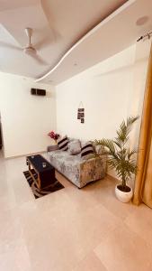a living room with a couch and a plant at Atulyam Stays Sushant Golf City in Lucknow
