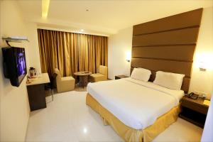 a hotel room with a large bed and a television at Hotel Sitara Grand Miyapur in Hyderabad