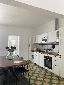 a kitchen with white cabinets and a wooden table at Casa Monte Tamissa in Vila Real de Santo António