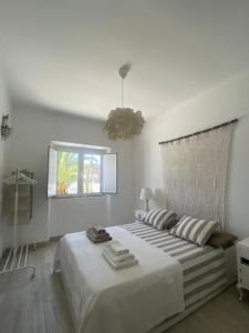a white bedroom with a large bed and a window at Casa Monte Tamissa in Vila Real de Santo António