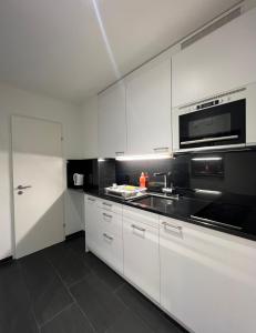 - une cuisine blanche avec évier et four micro-ondes dans l'établissement Seefeld Residenz, à Zurich