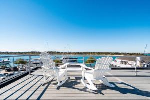 2 weiße Stühle und ein Tisch auf einem Dock mit einem Boot in der Unterkunft Why Knot Getaway...Rooftop with WaterView! Unit D in Beaufort
