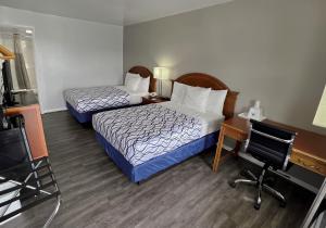 Habitación de hotel con 2 camas, escritorio y silla en America's Best Value Inn Lancaster, en Lancaster