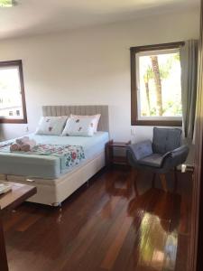 a bedroom with a bed and a chair and a window at Casarão Caborê in Paraty