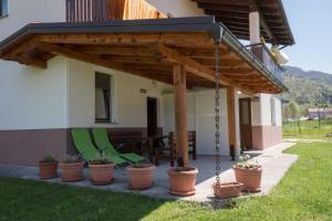a porch with a swing and chairs under awning at Apartment and Room Natasa in Kobarid