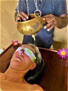 Eine Frau in einer Badewanne mit einer Schüssel auf dem Kopf. in der Unterkunft Ayurveda Suwetha Villa in Bentota