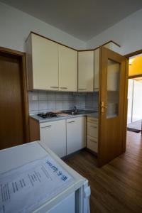 a kitchen with white cabinets and an open door at Apartment and Room Natasa in Kobarid