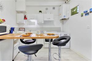 a kitchen with a wooden table and two black chairs at Tarbes Immeuble résidentiel labelisé et classé Proche des Halles Marcadieu et Brauhauban et du Parc des expositions - Appartements Appaloosa T2 Rdc et Pyrénéa T2 au 1er étage avec terrasse couverte -Parking gratuit- in Tarbes +13 photos