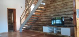 Habitación con pared de madera, TV y escalera. en Ventanas al Norte en Chascomús