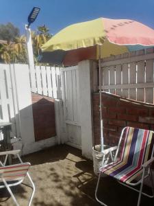 un patio con 2 sillas y una sombrilla en El Refugio de la Estancia, en Isla Negra