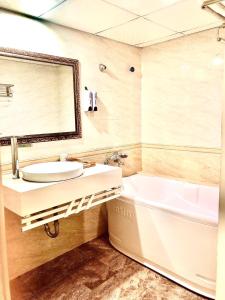 a bathroom with a sink and a tub and a mirror at Holiday Hotel 2 in Hai Phong