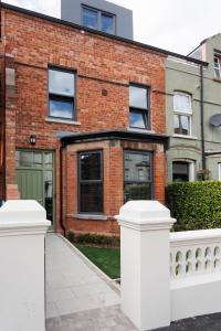 a brick building with a white fence in front of it at Boutique Stays at 78 in Bangor