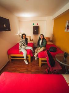 2 femmes assises dans une pièce avec des lits rouges dans l'établissement The Chusay Rooftop, à Cusco