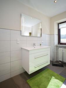 a white bathroom with a sink and a mirror at Ferienhaus an der Austwies in Nonnweiler