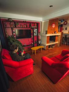 une femme assise sur un canapé rouge dans un salon dans l'établissement The Chusay Rooftop, à Cusco