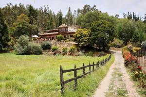 a house on a hill with a fence and a dirt road at Posada el portal de la Loma in Pesca