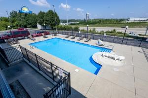a swimming pool with chairs and a fence around it at Days Inn by Wyndham Dayton Huber Heights Northeast in Huber Heights