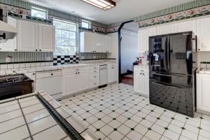 a kitchen with white cabinets and a black refrigerator at Eagle’s Landing Lodge in Custer