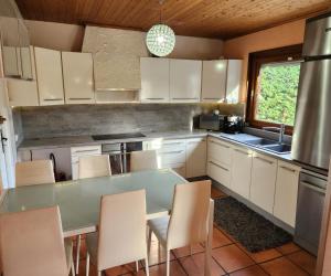 a kitchen with white cabinets and a table and chairs at VILLA "Le Jardin" 4 étoiles - Piscine chauffée couloir 12m - Spa Balnéo Hammam - 4 Chambres dont une Love Room de 35m2 avec lit rond, vidéo projecteur Netflix, climatisation in Jardin
