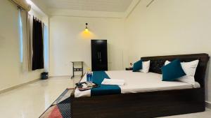 Schlafzimmer mit einem Bett mit blauen und weißen Kissen in der Unterkunft Atulyam Stays Sushant Golf City in Lucknow